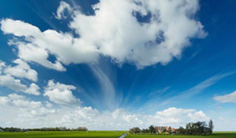 Typische Hollandse wolkenlucht met op de horizon een boerderij