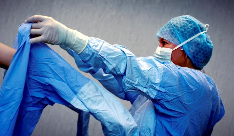 OK-Assistente helpt een collega in beschermende schort op de operatiekamer