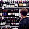 Vrouw voor schap met wijn in supermarkt