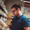 Een consument in de supermarkt leest de ingrediëntenlijst van een voedingsproduct